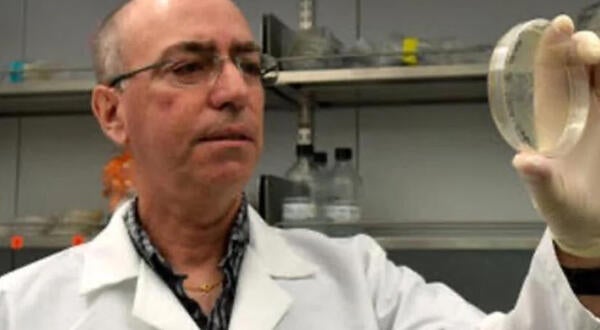 Ernest Martinez looking at petri dish in his lab