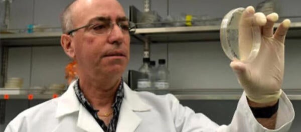 Ernest Martinez looking at petri dish in his lab